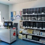 Wnętrze serwisu powerON w 2024 roku z regałami komputerów, ladą i miejscami siedzącymi dla klientów.