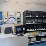 Stanowisko obsługi klienta z monitorem oraz regałami komputerów w serwisie powerON w 2024 roku.
