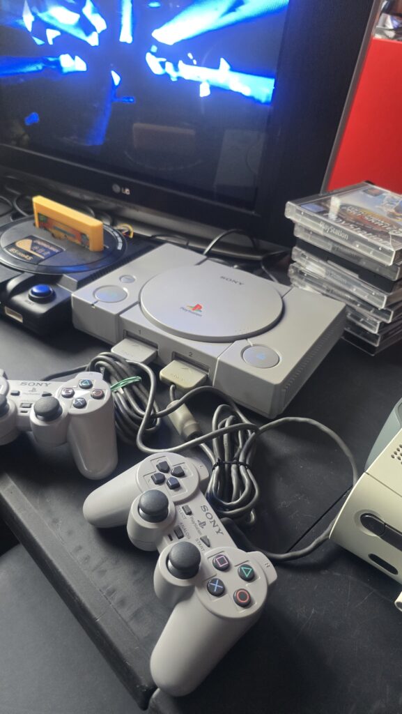Konsola Sony PlayStation 1 z dwoma kontrolerami, grami i telewizorem na wystawie RETRO powerON