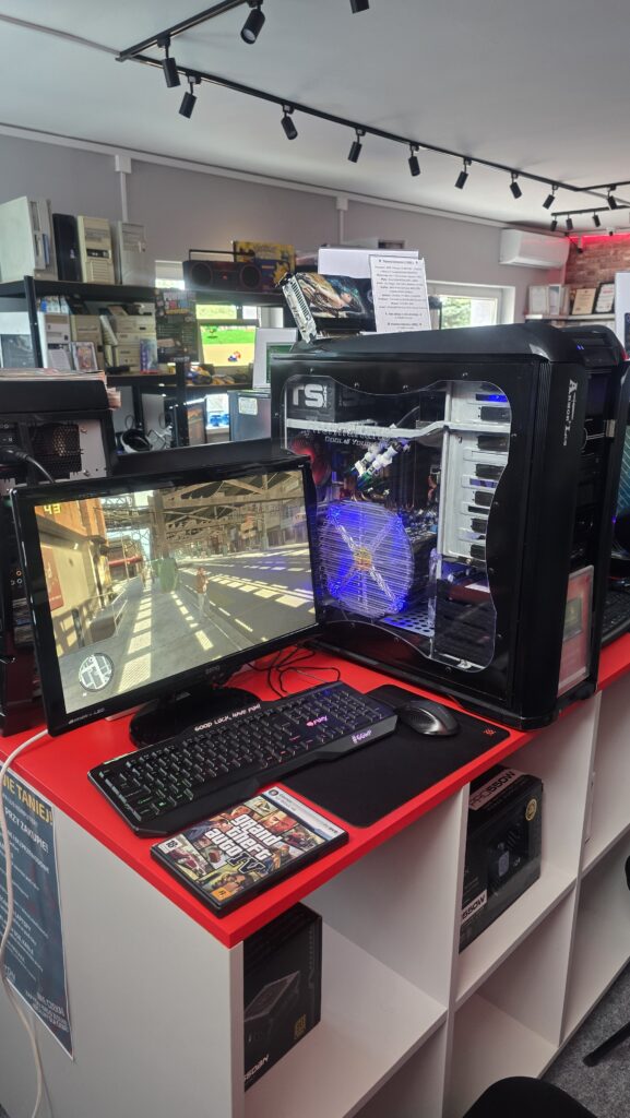 Stanowisko do grania z komputerem stacjonarnym, monitorem, klawiaturą i klasyczną grą na ekranie w sklepie powerON GTA IV